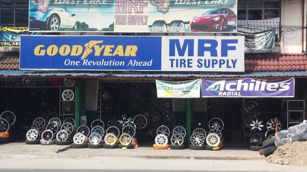A tire and wheel shop displaying various rims and tire brands, including Goodyear, MRF, and Achilles. Providing Excellence Car Care Services. - Leading Auto Experts in Pampanga