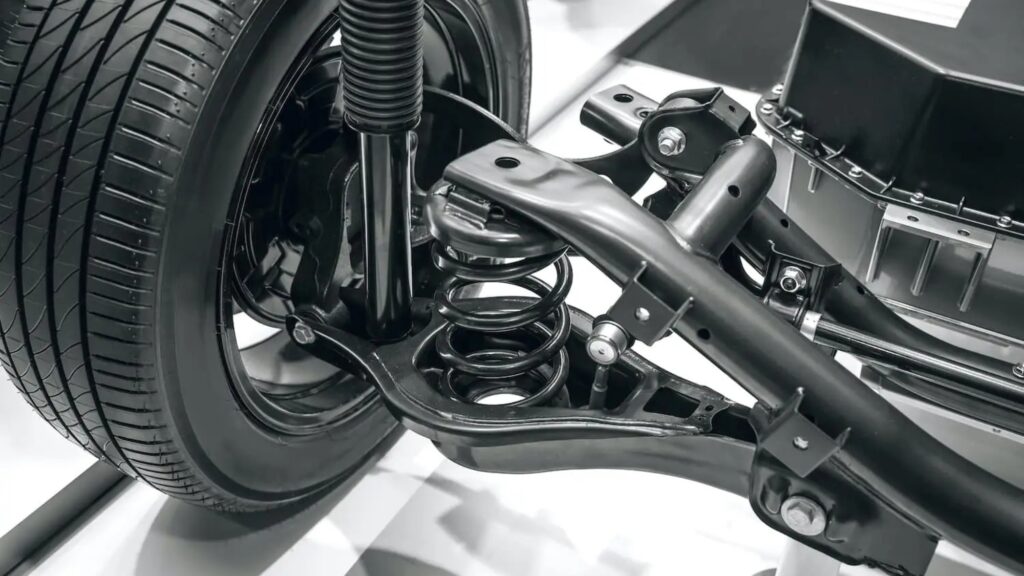 Close-up of a vehicle suspension system with a coil spring, control arm, and stabilizer bar, highlighting advanced engineering for improved stability and comfort.