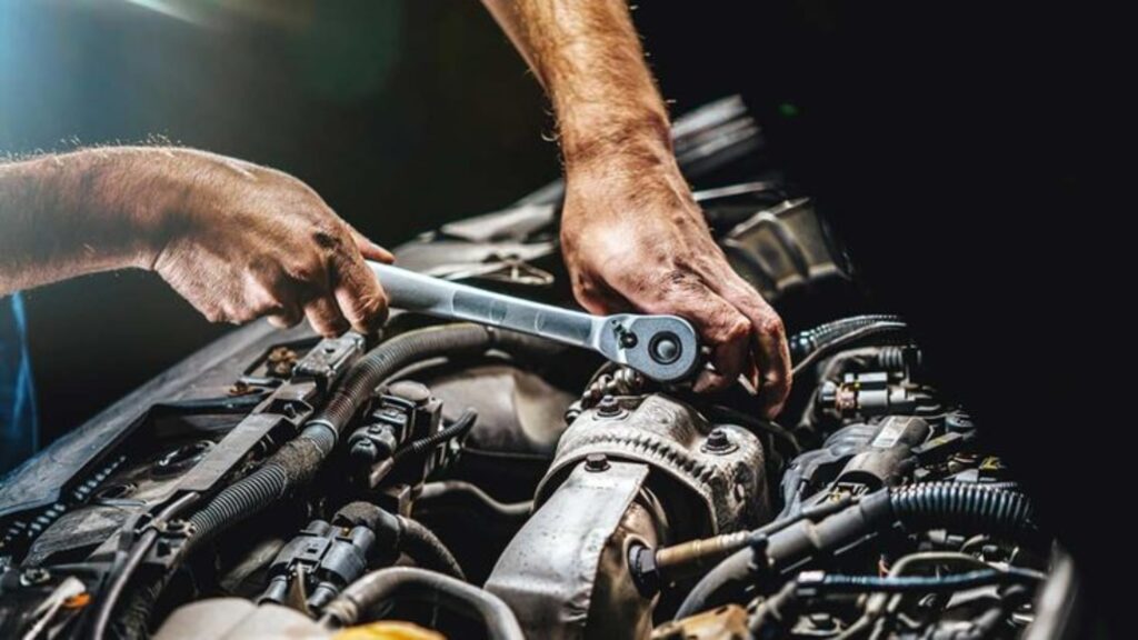 Mechanic's hands using a torque wrench on a car engine, demonstrating professional repair and maintenance work.