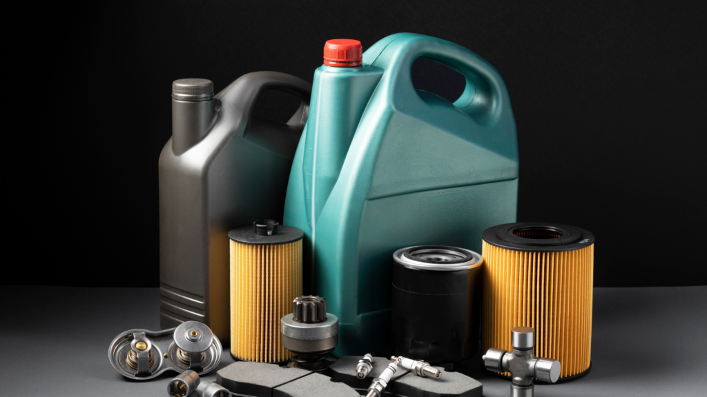 Various automotive maintenance supplies, including motor oil containers, oil filters, spark plugs, and other car parts, against a dark background.